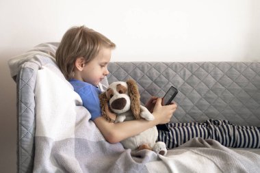 Çevrimiçi eğitim ve çalışma mesafesi. Çocuk eğitimi evden kanepeye kadar uzanıyor. Erkek eller tableti tutar.