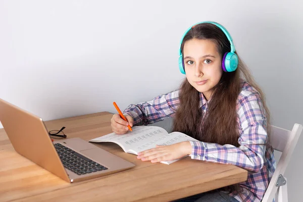 Aprendizaje a distancia en casa.Estudiante con un portátil que escucha un webinar en línea con auriculares. Concepto de aprendizaje electrónico . — Foto de Stock