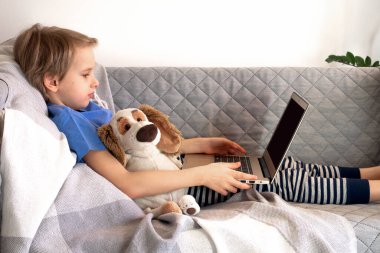 Çevrimiçi eğitim ve çalışma mesafesi. Çocuk eğitimi evden kanepeye kadar uzanıyor. Erkek eller dizüstü bilgisayarı tutar