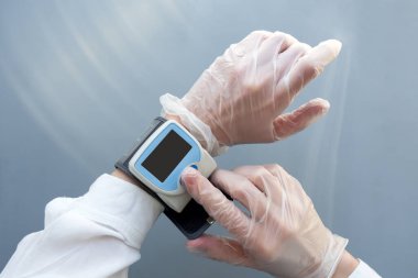 Tıbbi eldivendeki kadın elleri kan basıncı monitörü kullanıyor. Sağlık sigortası doktor konsepti. Model