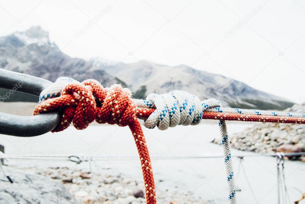 Iron twisted rope stretched between rocks in climbers patch via ferrata. Rope fixed in block by screws snap hooks. Detail of rope end anchored into sandstone rock.Shallow depth of field.