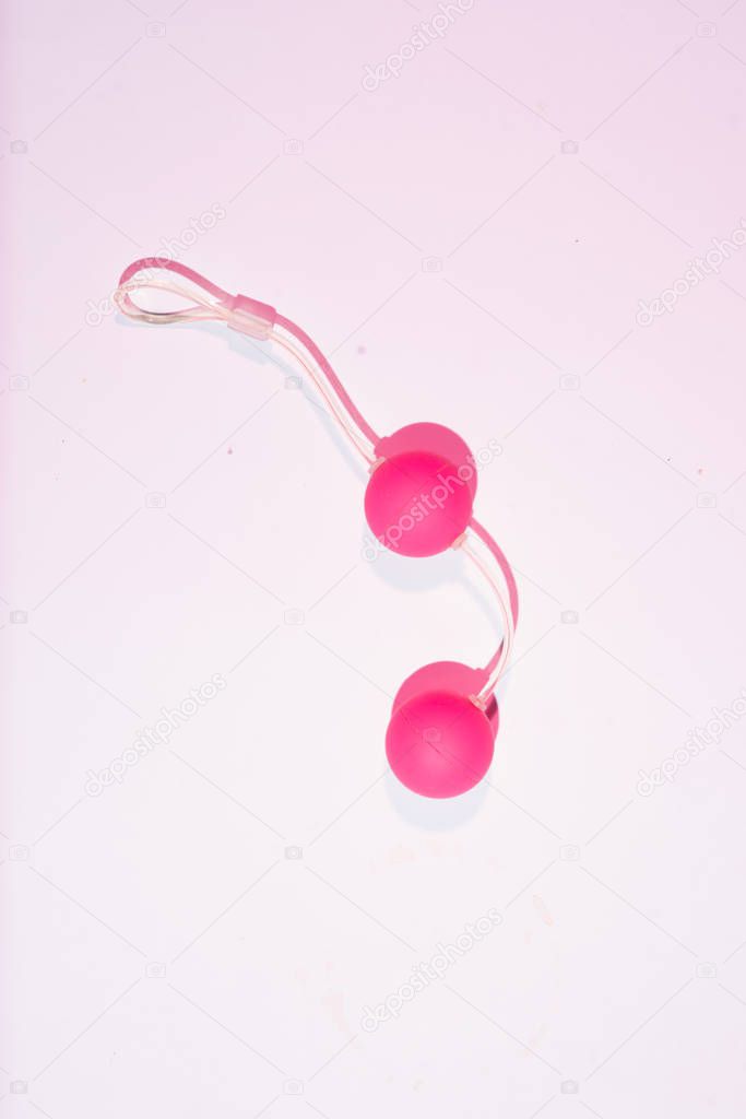 Sex toy kegel balls on a pink background, top view, flat layout 