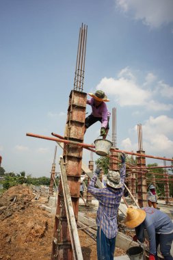 Ratchaburi, Tayland: 1 Mart 2018 - Bir grup işçi inşaat alanındaki ahşap modele karışık çimento dökerek evin temelini attılar