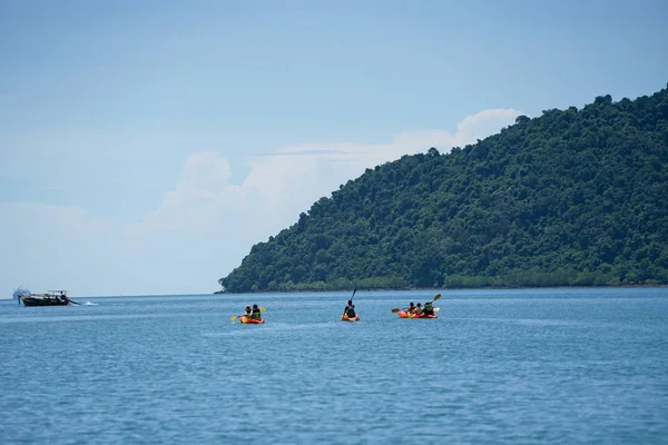 海の表面でカヌーをする旅行者のグループに焦点を当て、背景に海と島でツアーをする — ストック写真