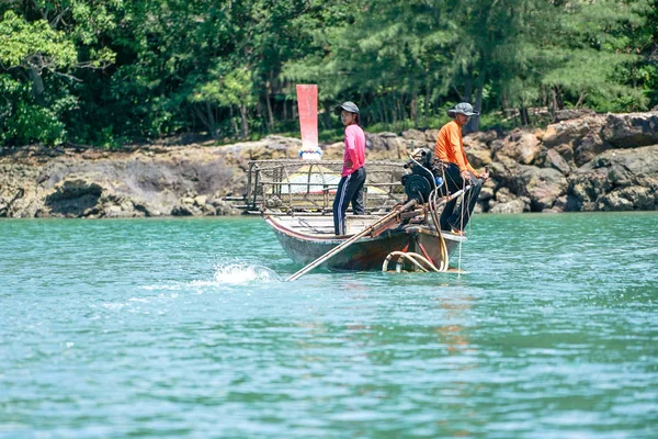 Ko Lanta, Krabi, Thailand:October 22, 2019 - Fishermen drive the traditional long-tail boat and find fish by tools in sunny day with defocused island in background — Stock Photo, Image