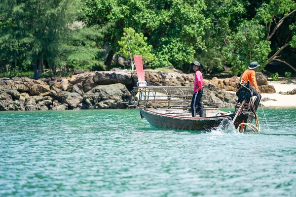 Ко Ланта (Ko Lanta), Краби (Krabi), Таиланд: 22 октября 2019 г. - Рыбаки ездят на традиционной лодке с длинным хвостом и находят рыбу с помощью инструментов в солнечный день на заднем плане с разряженным островом — стоковое фото