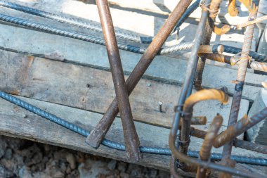 İnşaat alanında arka planda ahşap plaka ile güçlendirilmiş çeliği bükmek için kullanılan endüstriyel metal aletin üst görünümü