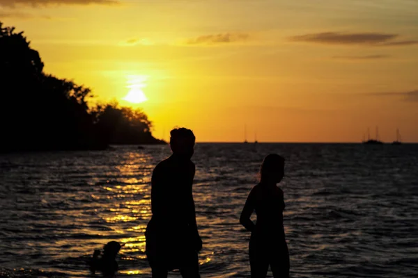 Retrato de silueta de dulce pareja caminando por la playa con luz de atardecer y horizonte borroso en el fondo — Foto de Stock