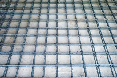 İnşaat alanının beton zeminini kaplayan beton yapı güçlendirme amaçlı çelik işçiliğinin en üst görüntüsü.