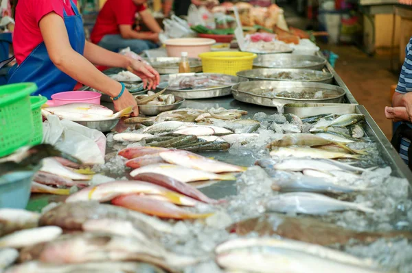 Selective focus on raw fresh fish on the tray for selling in the market with blurred seller in background — Stock Photo, Image