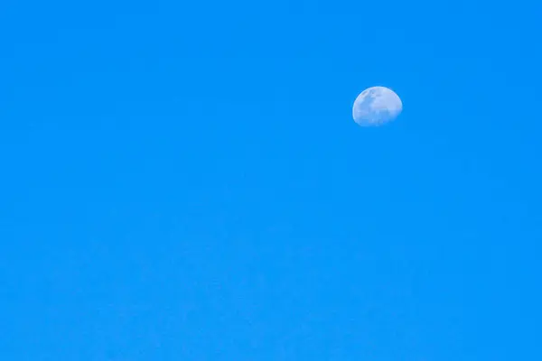 在阳光明媚的日子里 半月形的月亮在蓝天的背景上与世隔绝 — 图库照片