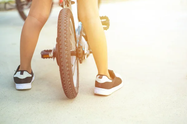 Closeup legs of boy stands over the small  bicycle during practicing with sunlight in background