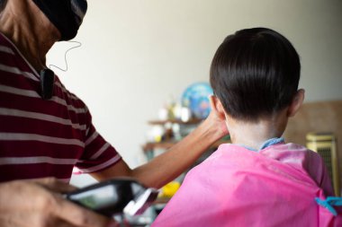 Küçük çocuğun arka portresinin garajında saç kesimi var. Arka planda bir sürü alet ve ekipman var.