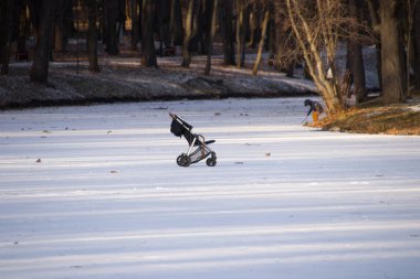 Bebek arabası gölün ilk ince buzunda duruyor.