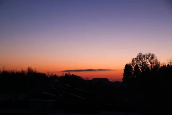 Winter sunset against the background of village houses and forests