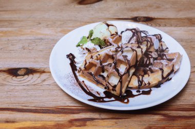 Vanilyalı dondurmayı ahşap masa üstünde waffle ile kapat.