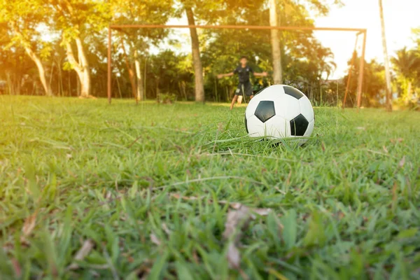 Мальчик пинает футбольный мяч на спортивном поле. Футбольный тренер — стоковое фото