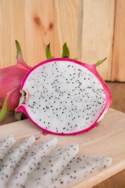 Tahta arka planda ejderha meyveleri, dilimlenmiş lezzetli ejderha meyveleri.