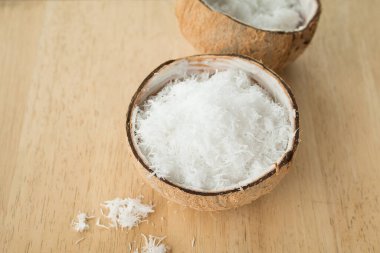 Ahşap masanın üzerinde taze rendelenmiş hindistan cevizini kabukla kapat..