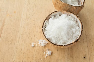 Ahşap masanın üzerinde taze rendelenmiş hindistan cevizini kabukla kapat..