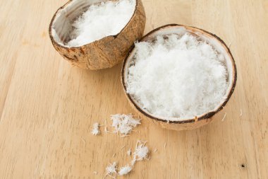 Ahşap masanın üzerinde taze rendelenmiş hindistan cevizini kabukla kapat..