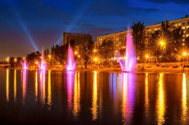 Renkli çeşmeler ve su yansıma, gece şehir manzaralı