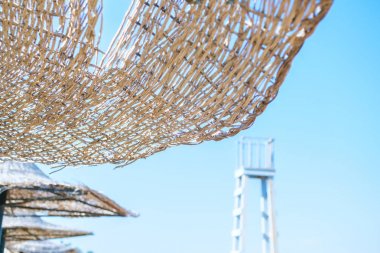Hasır plaj şemsiyesi gökyüzüne karşı. Tatil kavramı. Tasarım, metin için yer.