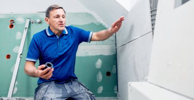 Profesyonel tiler duvara büyük format döşemeleri kuruyor. ev dekorasyonu. 