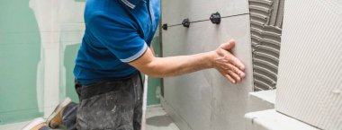 Duvara geniş bir format döşeme yerleştirirken kırpılmış görüntüler. ev dekorasyonu.