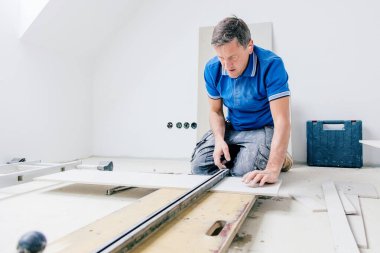 Odaklanmış orta yaşlı tiler duvara büyük format fayansları yerleştiriyor. ev dekorasyonu.