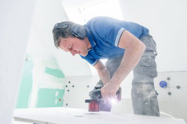 Koruyucu iş giysisinde tiler duvara büyük formatta fayanslar yerleştiriyor. ev dekorasyonu.