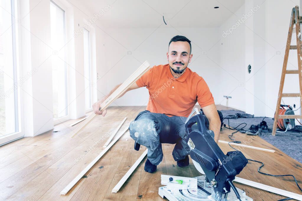 young man with a chop saw cutting skirting boards on a construction site. 
