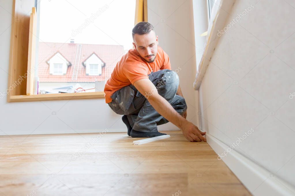 male worker cutting skirting boards on a construction site. Lay parquet floor  