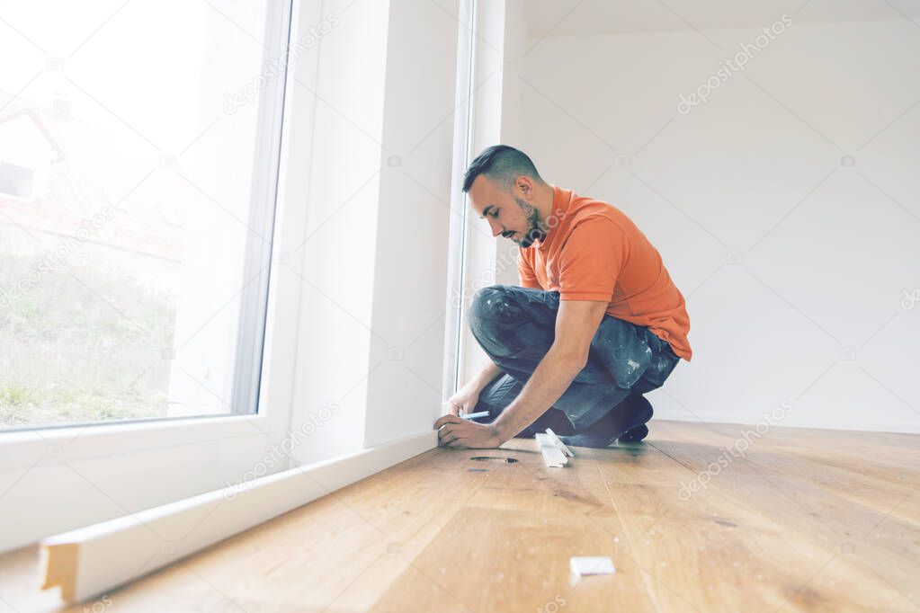 focused man cutting skirting boards on a construction site. Lay parquet floor 