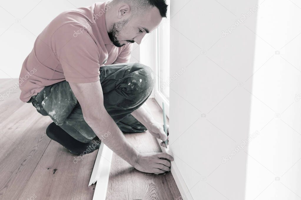 focused man cutting skirting boards on a construction site. Lay parquet floor 
