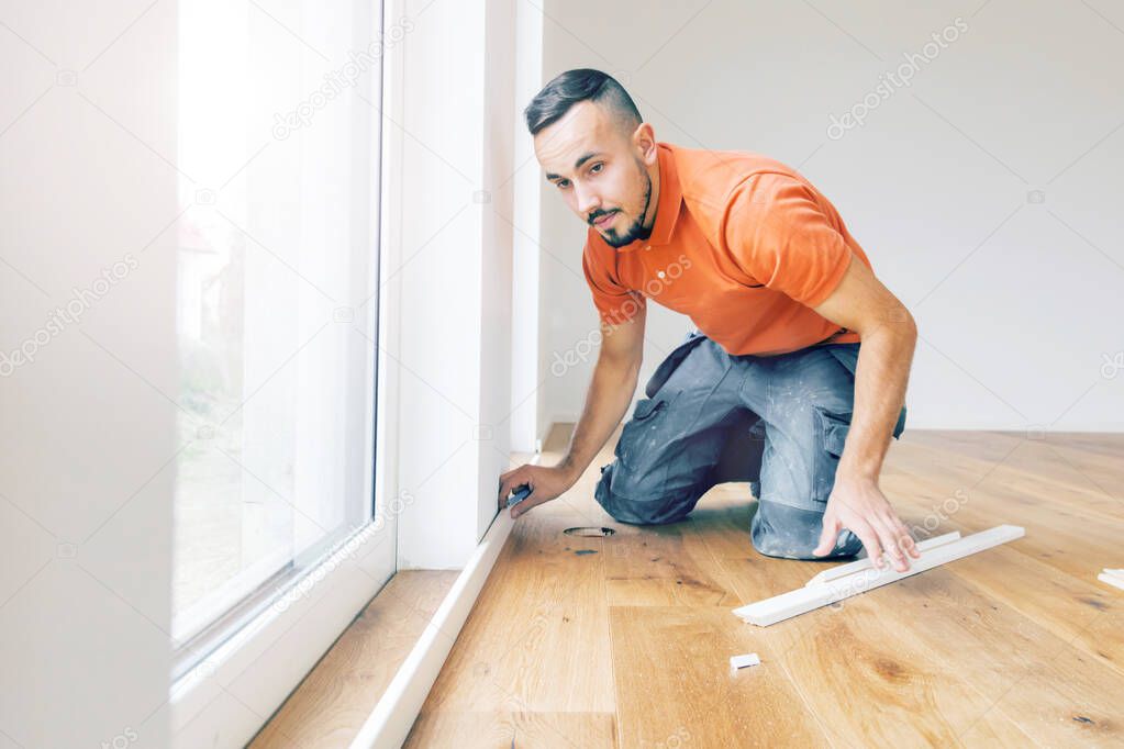 man cutting skirting boards on a construction site. Lay parquet floor