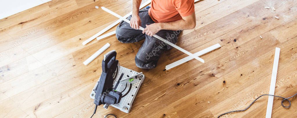 cropped shot of man installing oak parquet wooden floor during home improvement  