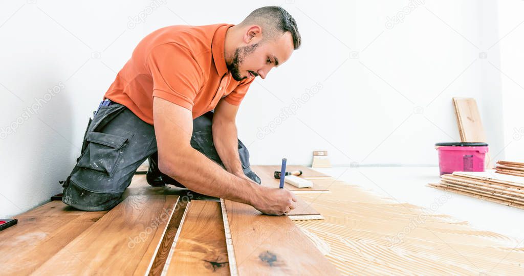 young male worker on construction site. Lay parquet floor   