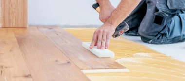 Erkek işçinin inşaat alanına parke döşeme kurarken çekilmiş görüntüleri. Parke döşeme   