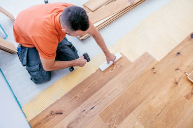 Erkek işçinin inşaat alanına parke döşeme görüntüsü yüksek açılı. Parke döşeme  