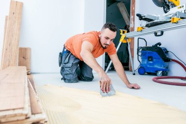 Erkek işçi inşaat alanına parke döşeme kuruyor. Parke döşeme  