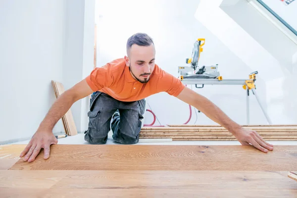 worker installing parquet floor on construction site. Lay parquet floor