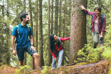 Sisli bir günde güzel dağlarda yürüyüş yapan sırt çantalı genç arkadaşlar.