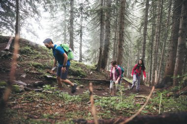 Sisli bir günde güzel dağlarda yürüyüş yapan sırt çantalı genç arkadaşlar.