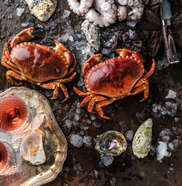 close-up view of crabs, octopus and oysters with ice on dark surface   
