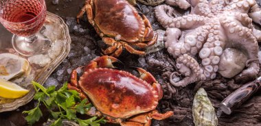 top view of crabs, octopus and oysters with ice and herbs on dark surface  