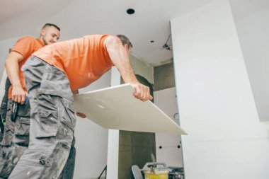 low angle view of professional tilers installing large format tiles. home indoors renovation clipart