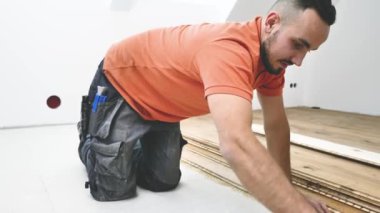 Erkek işçi inşaat alanına parke döşeme kuruyor. Parke döşeme 