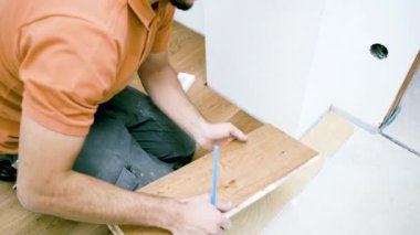 Erkek işçi inşaat alanına parke döşeme kuruyor. Parke döşeme 
