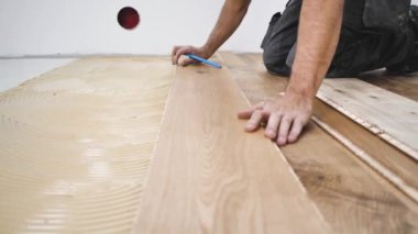 Erkek işçi inşaat alanına parke döşeme kuruyor. Parke döşeme 